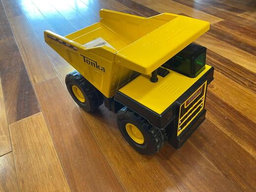 A toy yellow dump truck on a hardwood floor